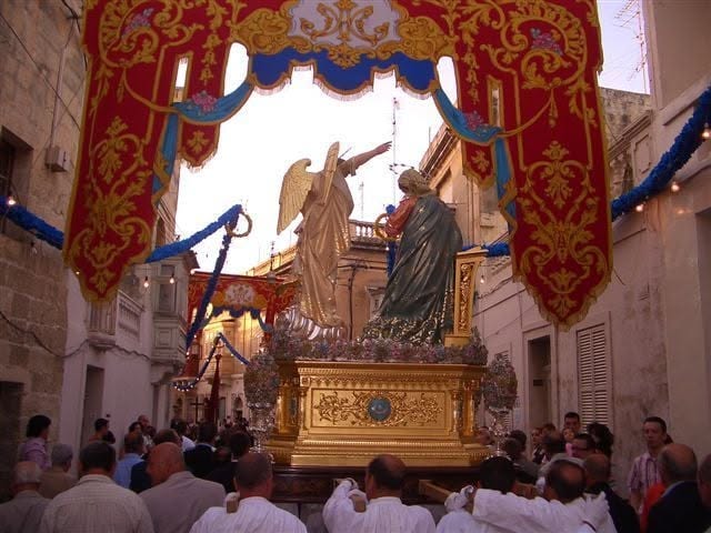 A procession beneath an ornate street banner