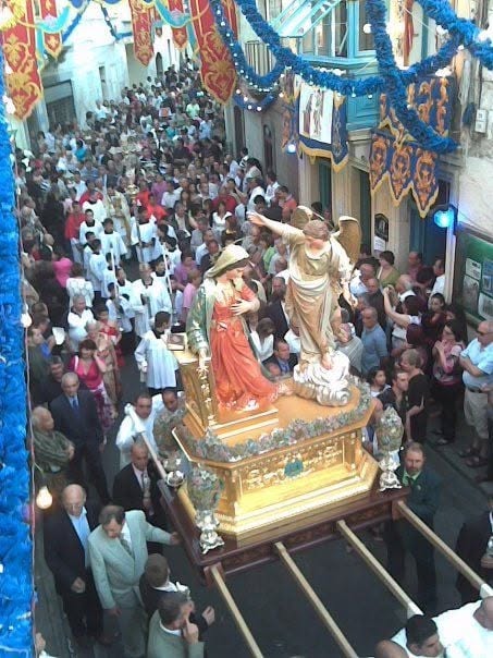 Annunciation statues in a crowded decorated street