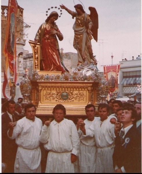 Statue bearers posing in front of the Annunciation statues