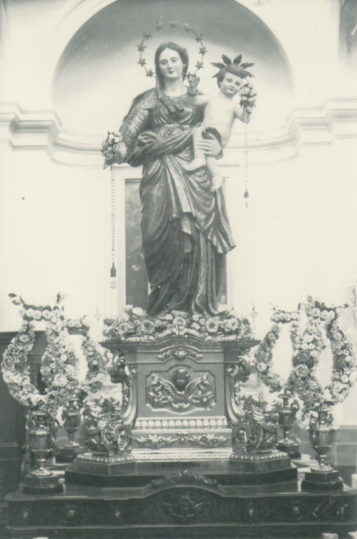 A statue of Mary and child surrounded by flowers